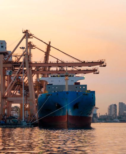 Container cargo ship in the export and import business and logistics international goods in urban city. Shipping cargo to the harbor by crane at sunset.